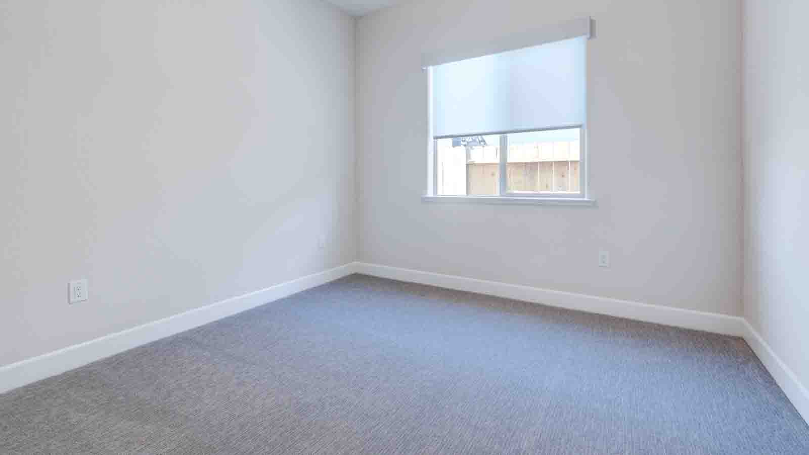 Bedroom with carpeted flooring and window blinds.