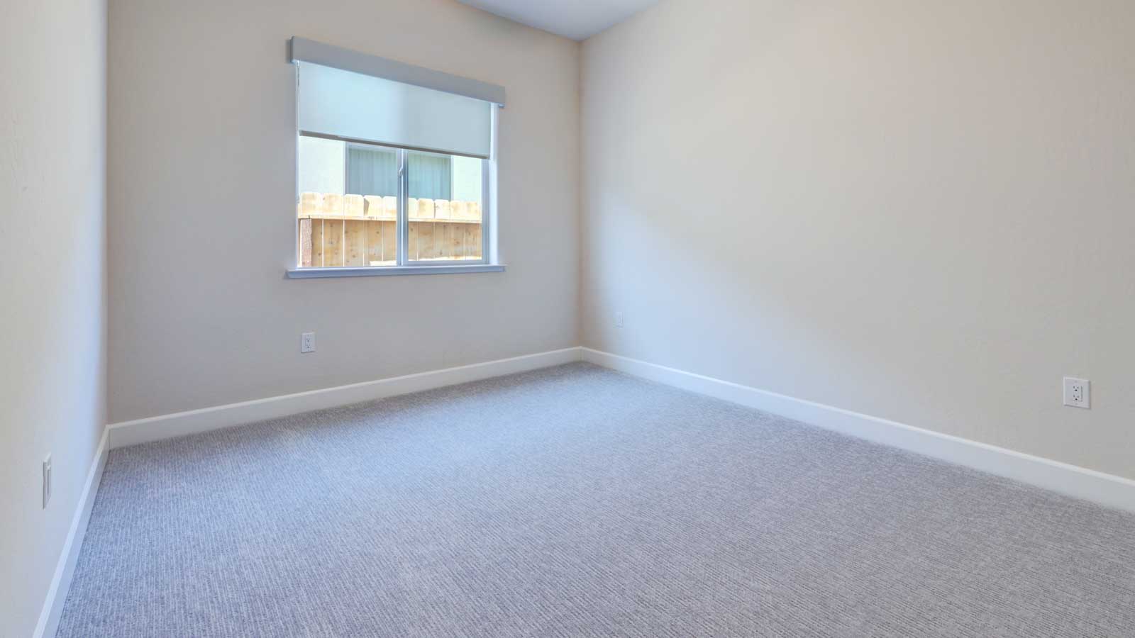 Bedroom with carpeted flooring and window blinds.