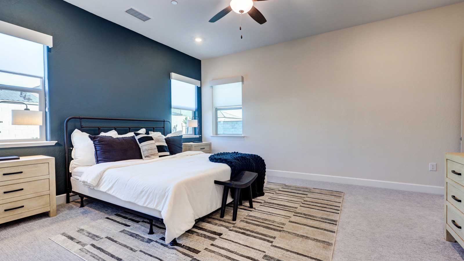 Owners suite with accent wall, window blinds and carpeted flooring.