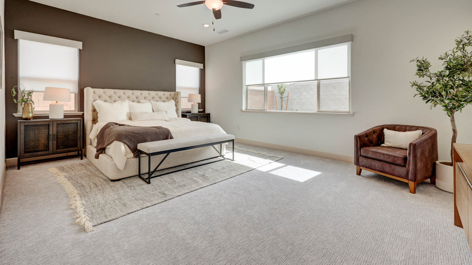 Large bedroom with carpeted flooring, window blinds, and adjoining bath.