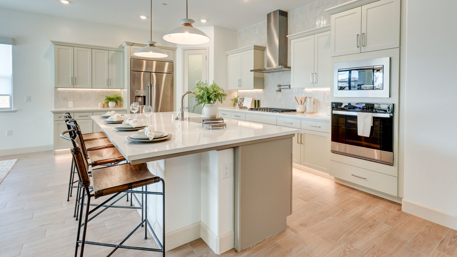 Kitchen with walk-in pantry, island with breakfast bar, stovetop pot filler and plank tile flooring.