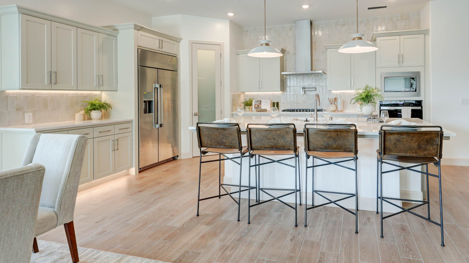 Kitchen with walk-in pantry, island with breakfast bar, stovetop pot filler and plank tile flooring.