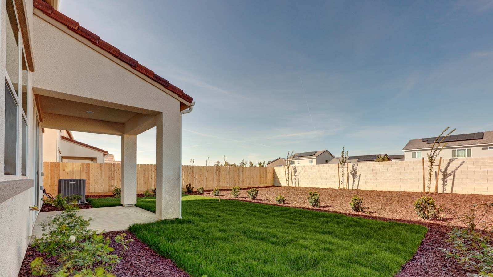 Rear yard with grass, bark, and covered patio