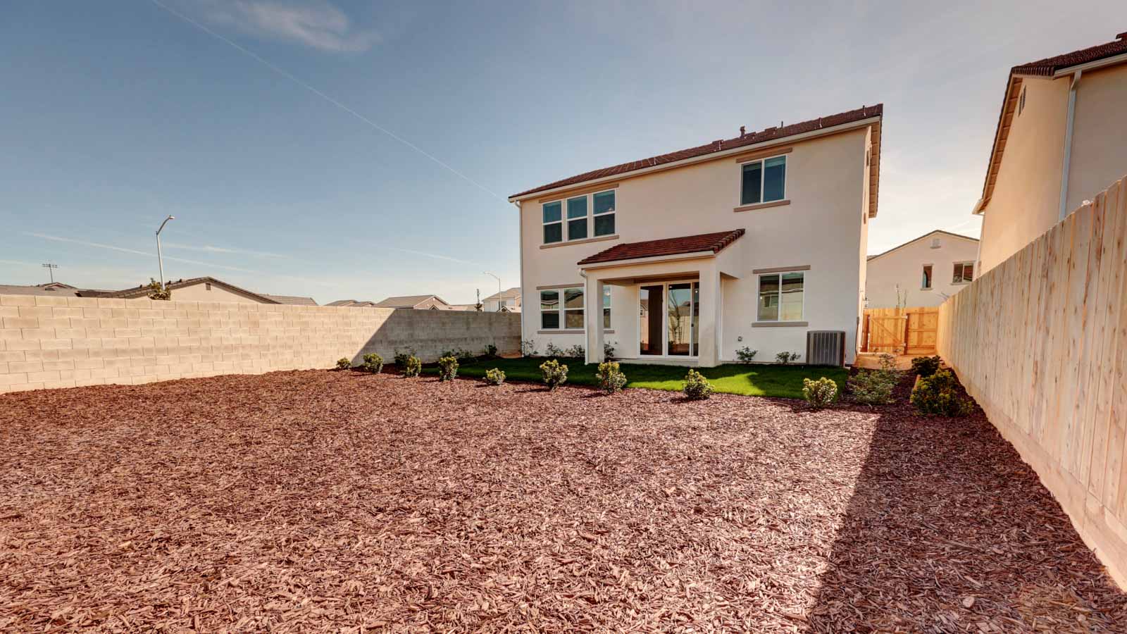 Rear yard with grass, bark, and covered patio